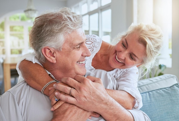 Amor feliz y pareja mayor abrazar y vincularse en el sofá sonreír y relajarse en casa juntos Libertad de jubilación y feliz hombre y mujer compartiendo un abrazo romántico disfrutando de la conversación y la relación