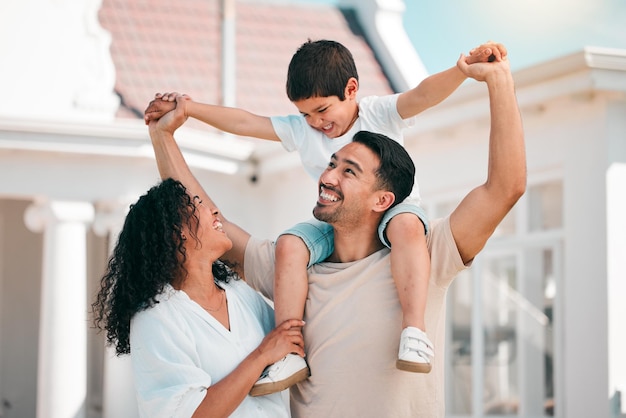 Amor feliz y unión familiar joven al aire libre en el patio trasero de su casa moderna Sonrisa de felicidad y niño jugando con sus padres en el jardín exterior para tomar aire fresco en su nuevo hogar