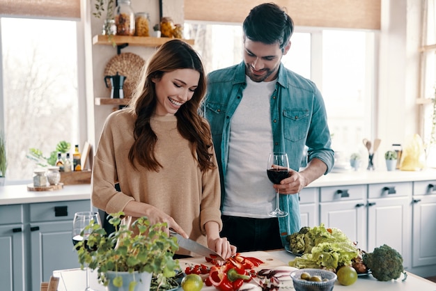 Amor sin fin. Hermosa joven pareja cocinando la cena mientras está de pie en la cocina de casa