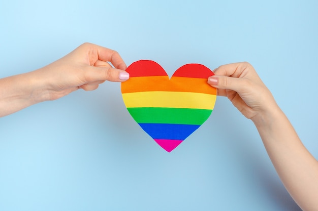 Amor gay. Mano humana sosteniendo un corazón de papel arcoiris