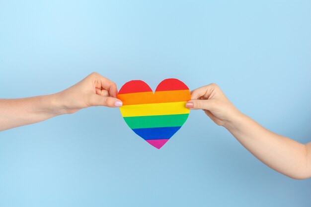 Amor gay. Mano humana sosteniendo un corazón de papel arcoiris