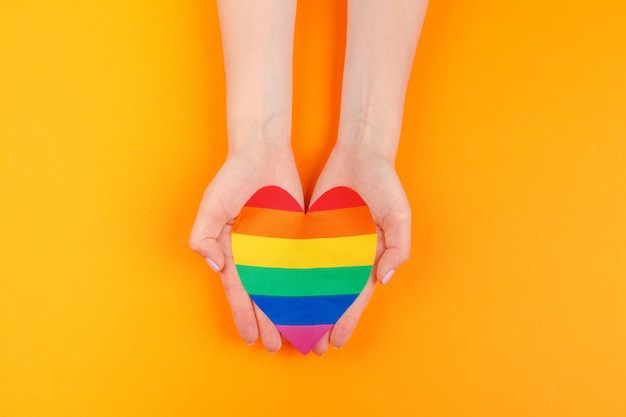 Amor gay. Mano humana sosteniendo un corazón de papel arcoiris