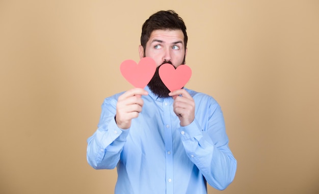 Foto el amor importa celebración de amor romántico hombre barbudo con corazones rojos hipster con corazones pequeños hombre sexy de san valentín con tarjetas en forma de corazón feliz día de san valentín