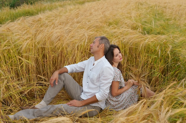 Amor infeliz pareja sentada en la hierba en un campo de trigo. El hombre y la mujer se pelearon.