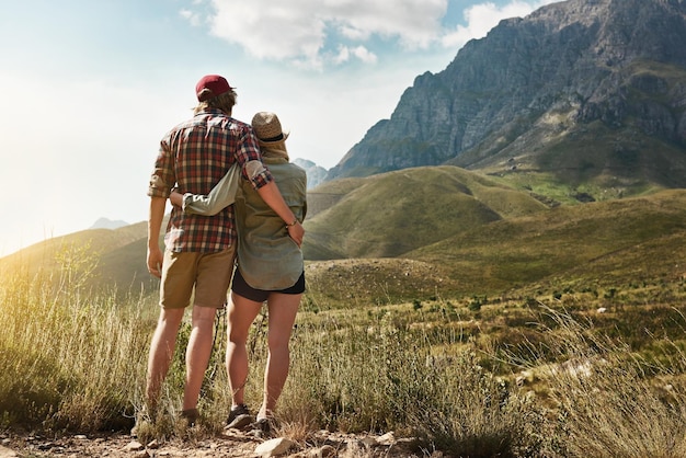 Amor inspirado por la belleza de la naturaleza Vista trasera de una pareja joven admirando una vista montañosa en la naturaleza