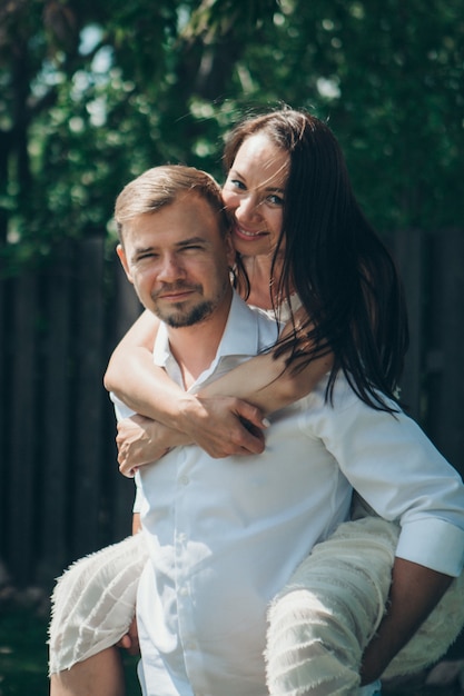 El amor de un joven marido y mujer, caras felices, una cita en la naturaleza, alegría, un chico monta a una chica en su espalda. Amor por siempre Romance joven