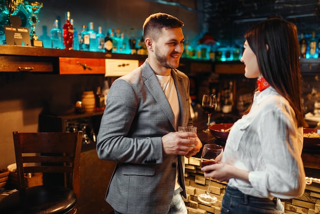 Amor pareja con bebidas alcohólicas hablando en barra de bar, velada romántica de hombre y mujer.