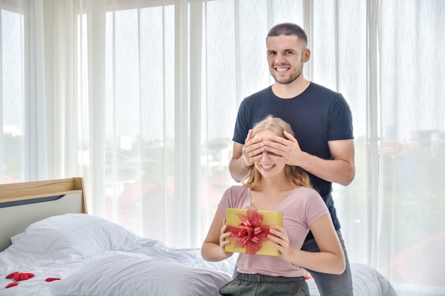 Amor pareja dando caja de regalo en el dormitorio felicidad en el amor concepto de San Valentín