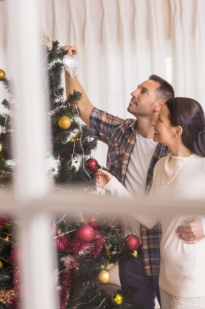 Amor pareja decorando el árbol de Navidad juntos