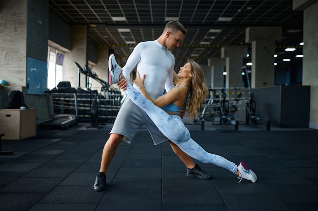 Amor pareja haciendo ejercicio de estiramiento en el gimnasio