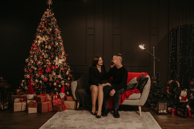 Amor pareja hombre y mujer abrazándose besándose cerca del árbol de Navidad