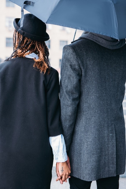 Amor pareja en vista posterior del día lluvioso. Estilo de moda. Gente elegante irreconocible en tela gris y negra, clima cambiante, relación fuerte