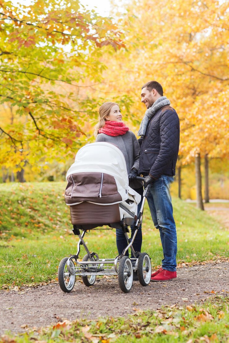 Foto amor, paternidade, família, temporada e conceito de pessoas - casal sorridente com carrinho de bebê no parque outono