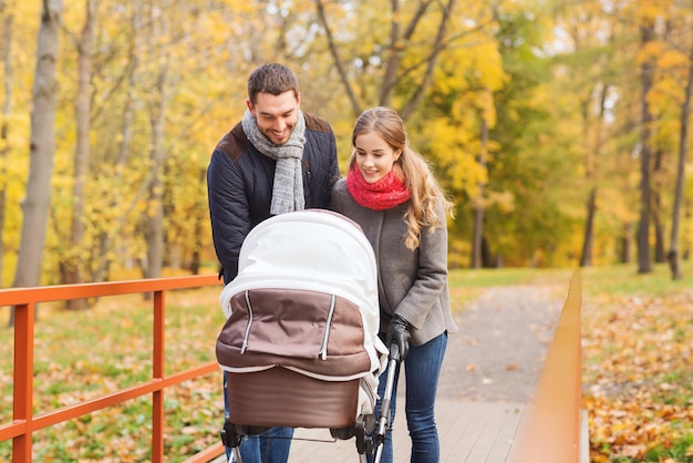 amor, paternidade, família, temporada e conceito de pessoas - casal sorridente com carrinho de bebê no parque outono