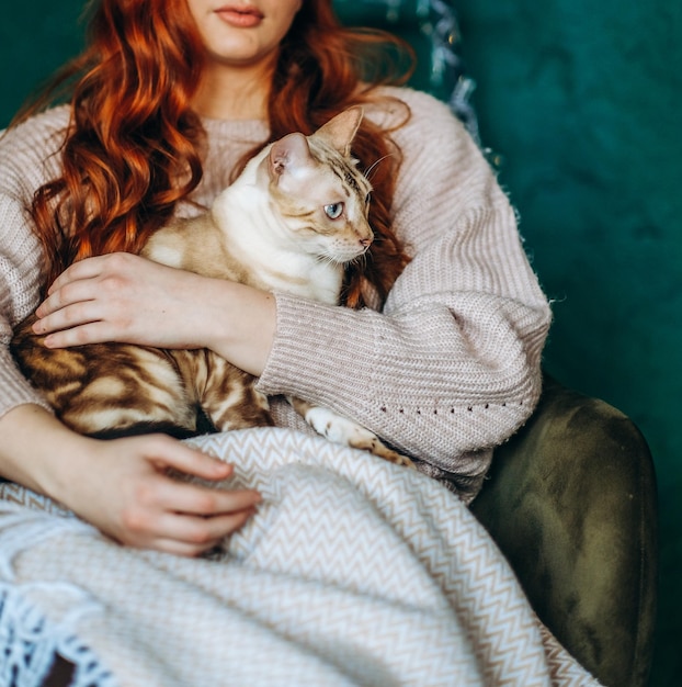 Amor por gatos uma mulher se senta em uma cadeira em casa e segura seu amado gato bengal em seus braços