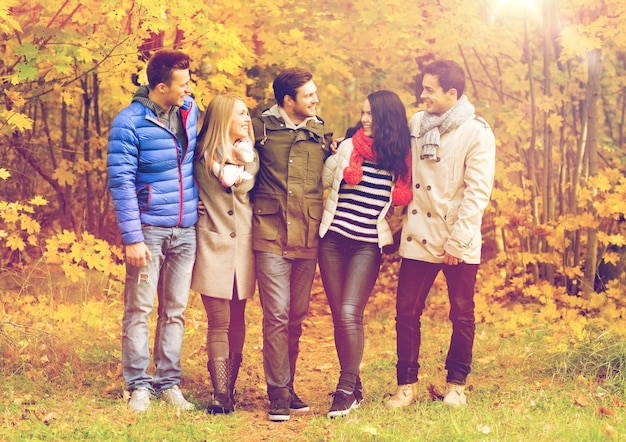 amor, relación, temporada, amistad y concepto de personas - grupo de hombres y mujeres sonrientes abrazándose en el parque de otoño