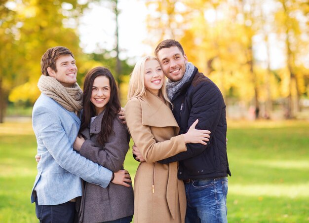 amor, relación, temporada, amistad y concepto de personas - grupo de hombres y mujeres sonrientes abrazándose en el parque de otoño