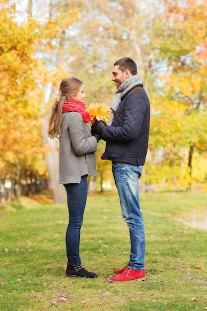 amor, relacionamento, família, temporada e conceito de pessoas - casal sorridente com monte de folhas no parque outono