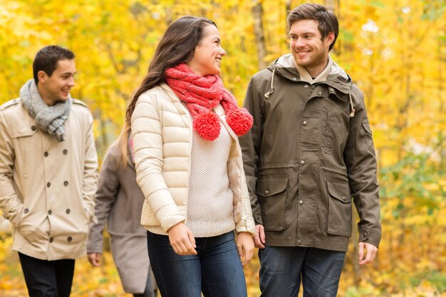 amor, relacionamento, temporada, amizade e conceito de pessoas - grupo de homens e mulheres sorridentes caminhando no parque outono