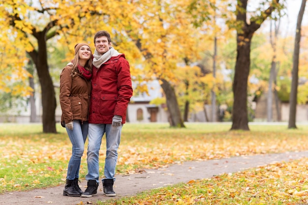 amor, relacionamentos, temporada e conceito de pessoas - casal jovem feliz caminhando no parque outono