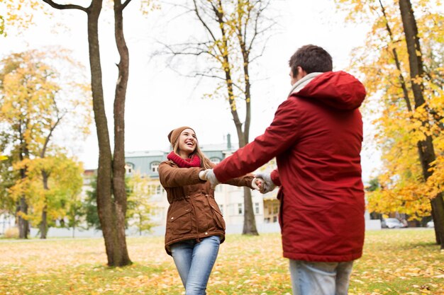 amor, relacionamentos, temporada e conceito de pessoas - casal jovem feliz se divertindo no parque outono