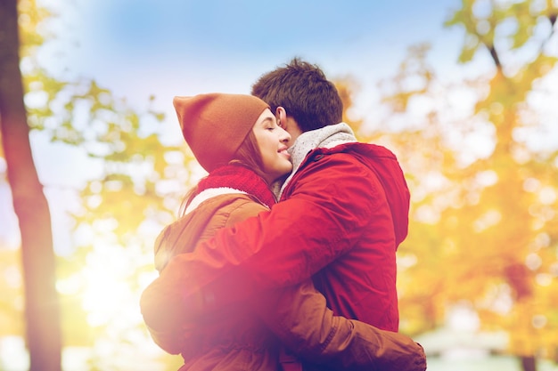 Foto amor, relaciones, estaciones y conceptos de personas - feliz pareja joven abrazándose en el parque de otoño