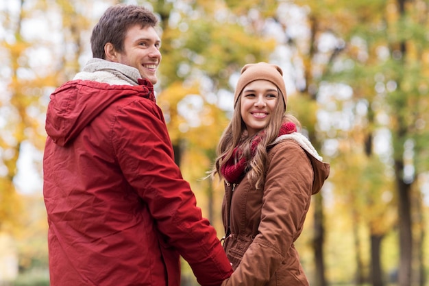 el amor, las relaciones, la temporada y el concepto de la gente - feliz pareja joven caminando en el parque de otoño