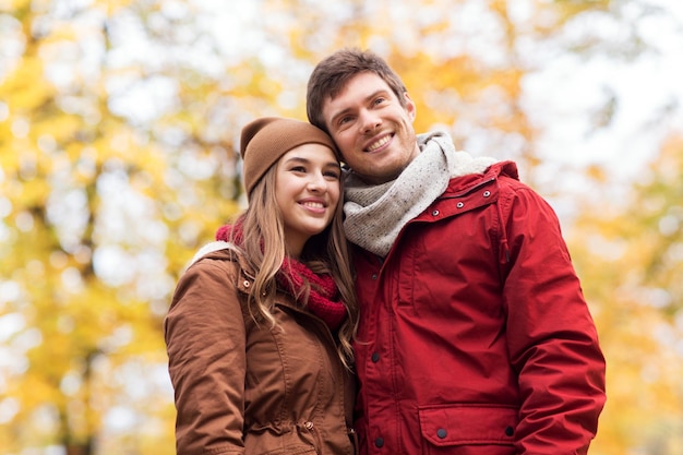 el amor, las relaciones, la temporada y el concepto de la gente - feliz pareja joven caminando en el parque de otoño