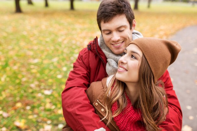 amor, relaciones, temporada y concepto de personas - feliz pareja joven abrazándose en el parque de otoño