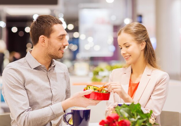 amor, romance, dia dos namorados, conceito de casal e pessoas - casal jovem feliz com flores vermelhas e caixa de presente aberta no shopping café