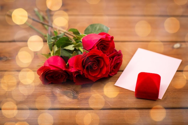 amor, romance, día de san valentín y concepto de vacaciones - cierre de caja de regalo, rosas rojas y tarjeta de saludo en madera