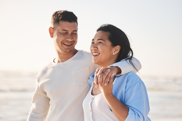 Amor, sorriso e abraço com casal na praia para viagens, férias de verão e romance juntos Feliz relaxamento e vínculo com homem e mulher caminhando nas férias à beira-mar para encontro de cuidados e lua de mel