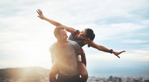 El amor y la vida lo abrazan con los brazos abiertos Foto de una joven pareja feliz disfrutando de un paseo a cuestas al aire libre