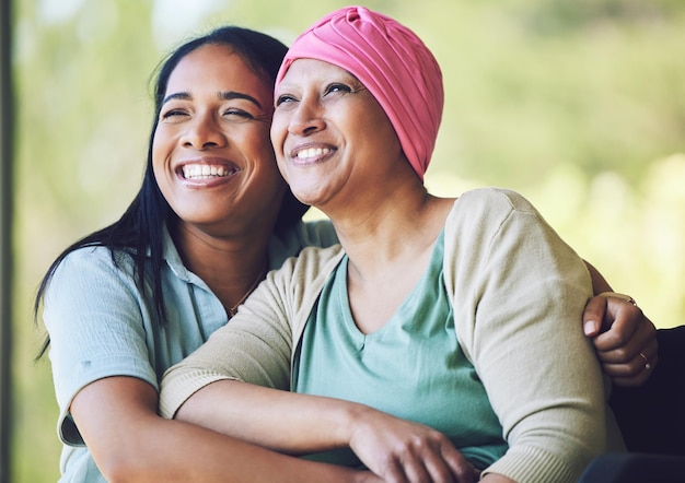 Amor vinculación y mujer con su madre con cáncer abrazándose sentados y pasando tiempo juntos Feliz dulce y enferma mujer madura abrazando a su hija adulta con una sonrisa en el jardín al aire libre