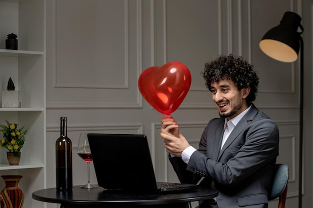 Amor virtual bonitão bonito de terno com vinho em um encontro de computador à distância segurando balão de coração