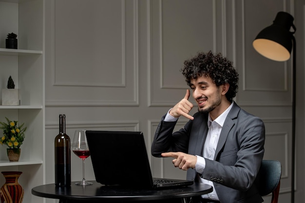 Amor virtual guapo chico lindo en traje con vino en una cita de computadora a distancia haciendo gesto de llamada