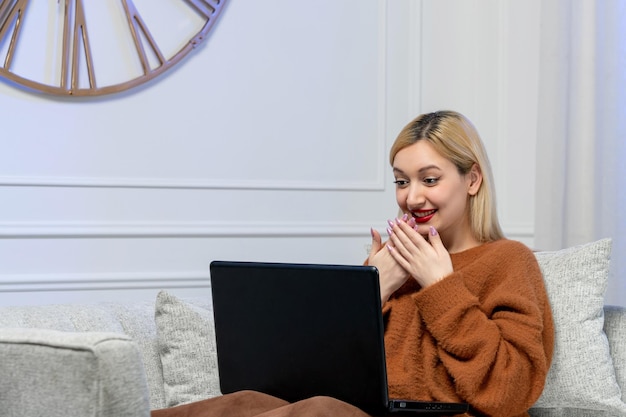 Amor virtual linda jovencita rubia en un suéter acogedor en la cita a distancia de la computadora emocionada