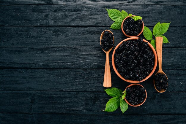 Amoras de frutas frescas em um fundo preto de madeira Vista superior Espaço livre para texto