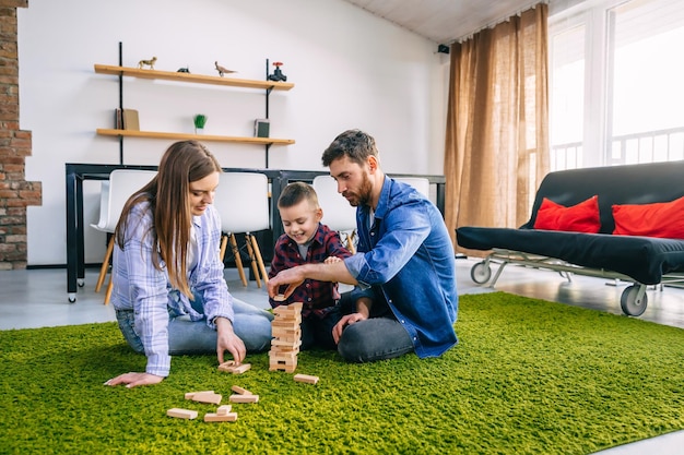 Amorosa familia jugando cubos en el suelo con un niño pequeño