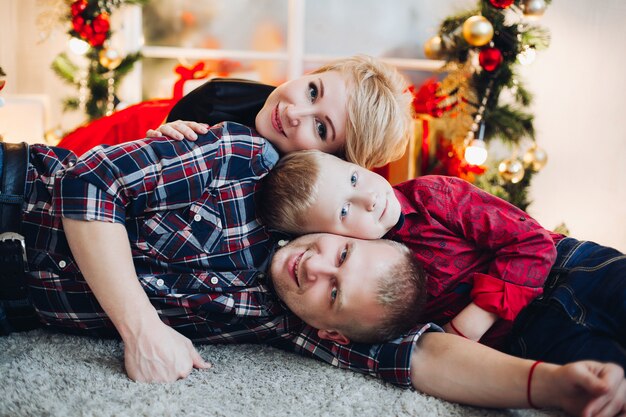 Amorosa familia tendida en el suelo contra la decoración de Navidad.