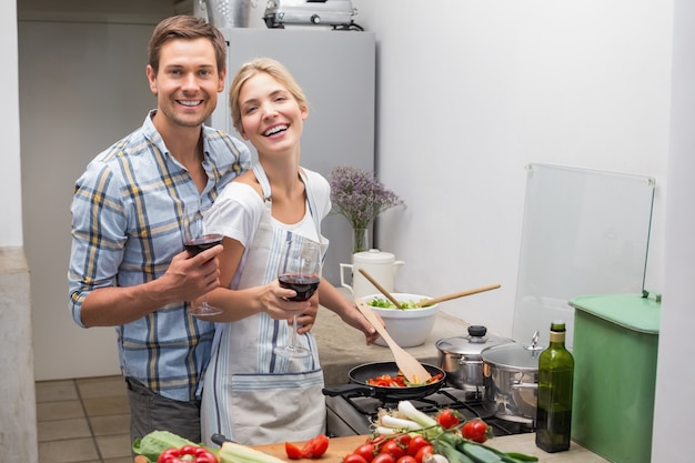 Amorosa jovem casal com copo de vinho na cozinha