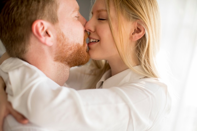 Amorosa joven pareja besándose en la habitación