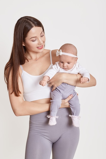 La amorosa madre europea joven sostiene al pequeño niño recién nacido, disfrutando el momento juntos, la madre cariñosa abraza al pequeño bebé, la maternidad, el cuidado de los niños, aislado sobre fondo blanco.