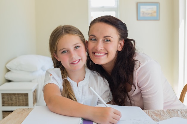 Amorosa madre con hija estudiando en la mesa