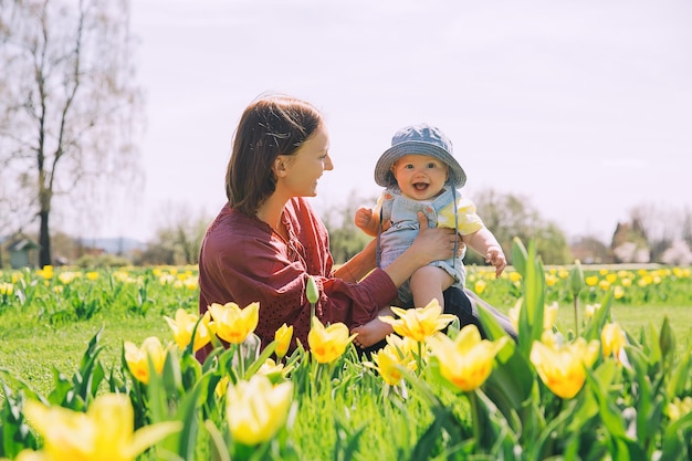 Amorosa madre y niña entre flores de tulipanes amarillos Mujer con su hija jugando al aire libre en el parque de primavera Familia en la naturaleza Imagen del Día de la Madre Campo de tulipanes de Pascua en Arboretum Eslovenia