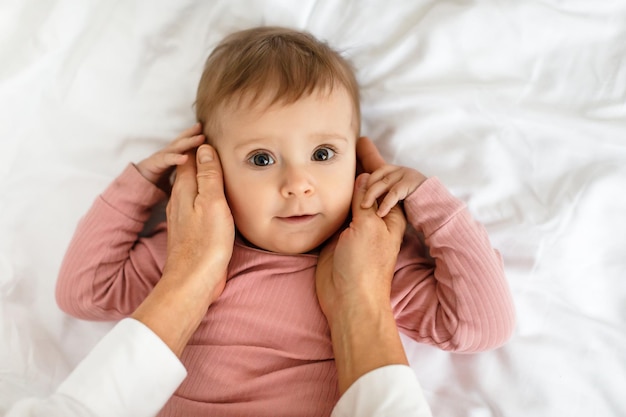 Foto amorosa madre vinculación con adorable niña tocando sus mejillas niño acostado en la cama vista superior primer plano