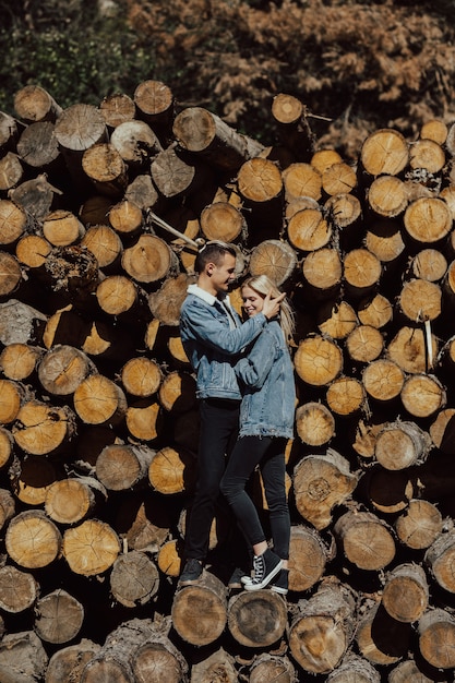 Amorosa pareja abrazándose sonriendo y sentirse feliz en los troncos talados en el bosque.