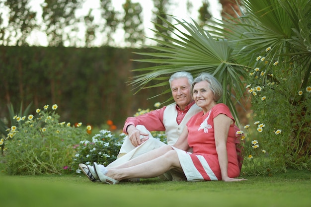 Amorosa pareja de ancianos sentados sobre un fondo de flores