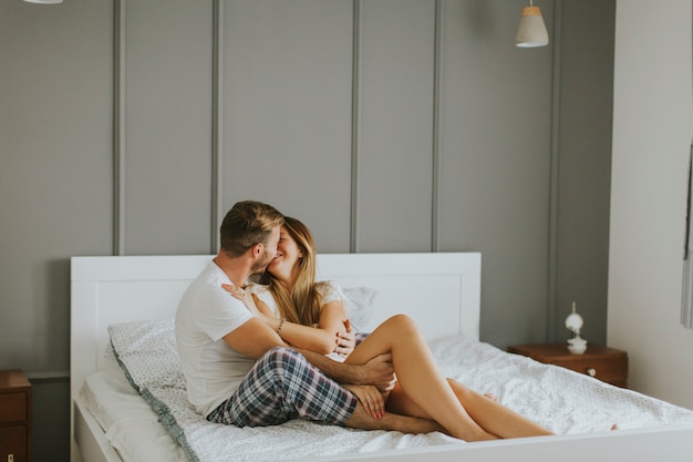 Amorosa pareja besándose en la cama en la habitación