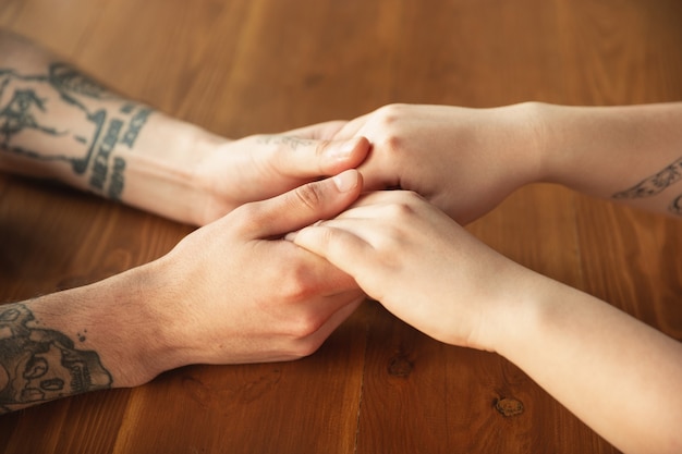 Amorosa pareja caucásica cogidos de la mano de cerca en la pared de madera. Romántico, amoroso, relación, cariño tierno. Mano de apoyo y ayuda, familia, cálida. Unión, sentimiento y emociones.